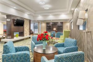 a lobby with blue chairs and a table with flowers at Best Western Plus New Englander in Woburn