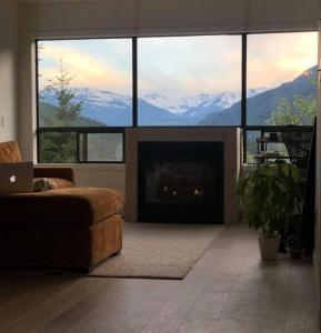 a living room with a fireplace with a view of mountains at Amazing Views 2 BR/2 BA Ski In Ski Out Condo in Whistler