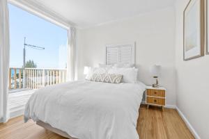 een witte slaapkamer met een bed en een groot raam bij Shore to Adore: Ocean Views & WiFi in Lulworth