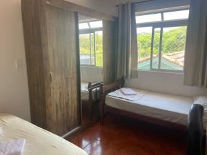 Habitación pequeña con 2 camas y ventana en Residencial Mizinho, en Florianópolis