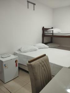 Cette chambre comprend 2 lits et une chaise. dans l'établissement Flat para 4 pessoas bem pertinho da praia de Geriba, à Búzios
