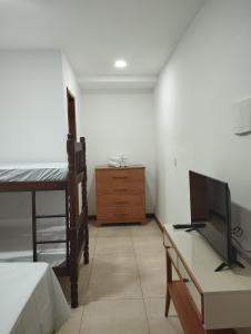 een slaapkamer met een bed, een tv en een bureau bij Flat para 4 pessoas bem pertinho da praia de Geriba in Búzios