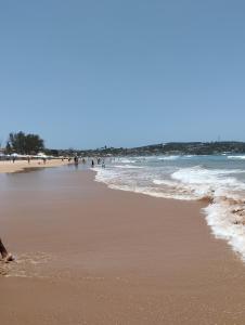 a beach with a group of people in the water at Flat para 4 pessoas bem pertinho da praia de Geriba in Búzios