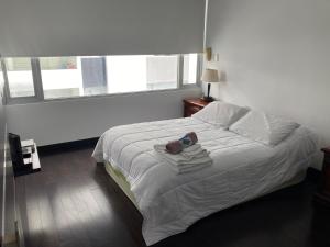 a white bed in a bedroom with a window at Suite con Jacuzzi - Torres el Bosque, Quito in Quito
