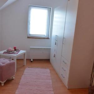 Habitación con armario blanco, mesa y ventana en Apartman Armenia, en Vrnjci