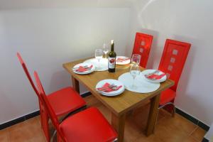 una mesa de madera con sillas rojas y una botella de vino en Apartman Armenia, en Vrnjci
