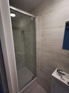 a shower with a glass door next to a sink at The Old Guest House, Norbury Avenue in Norbury