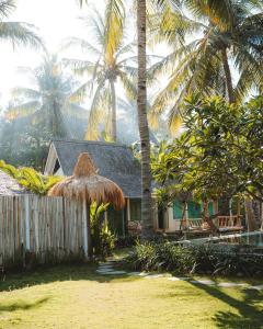uma casa com telhado de palha e palmeiras em Captain Coconuts Gili Air em Gili Air