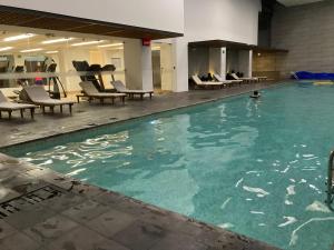 a large swimming pool with chairs in a building at Suite con Jacuzzi - Torres el Bosque, Quito in Quito