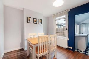 a dining room with a table and a kitchen at Cosy 2-bedroom house in Croydon in Croydon