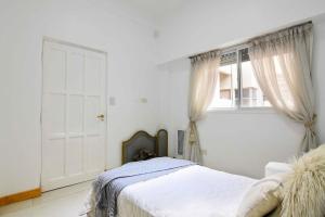 Un dormitorio blanco con una cama y una ventana. en Dpto. en Recoleta: cálido, próximo y confortable, en Buenos Aires