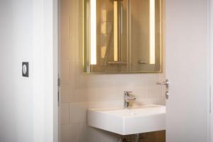 La salle de bains est pourvue d'un lavabo blanc et d'un miroir. dans l'établissement Best Western 11BAUER Paris Saint-Ouen, à Saint-Ouen
