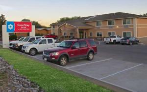 un SUV rosso parcheggiato in un parcheggio di fronte a un hotel di SureStay Plus by Best Western Montrose a Montrose