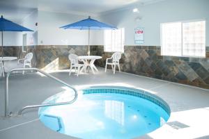 a swimming pool with a table and chairs and an umbrella at SureStay Plus by Best Western Montrose in Montrose