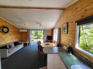 une cuisine et un salon d'une maison aux murs en bois dans l'établissement Off The Beaten Trail Acc & Bike Tours, à Murchison