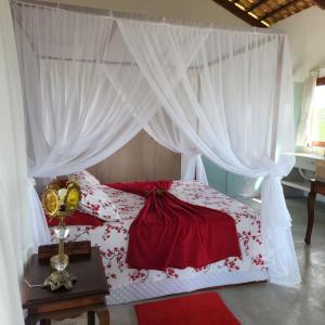 Un dormitorio con una cama roja y blanca con cortinas en Chalé romântico, com vista panorâmica, para Casais, en Monte das Gameleiras