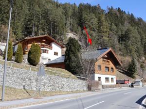 a house on the side of a road next to a stone wall at Apart Loisa in Pettneu am Arlberg