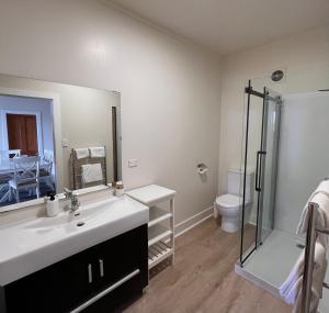 La salle de bains est pourvue d'un lavabo, d'une douche et de toilettes. dans l'établissement Mangonui Waterfront Apartments, à Mangonui