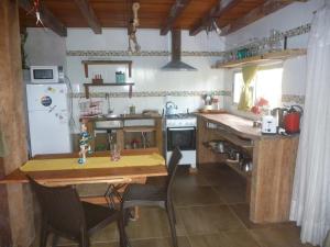 cocina con mesa de madera, sillas y nevera en IDALIA, en Barra del Chuy