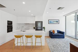 a kitchen with a counter and two bar stools at Belle Escapes - Sea the Views in Glenelg