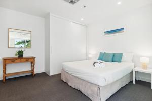 a white bedroom with a bed and a table at Belle Escapes - Sea the Views in Glenelg +24 photos