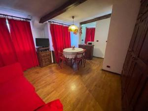 a living room with a table and red curtains at Grazioso monolocale in Borgata Sestriere
