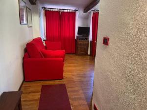 a living room with a red couch and red curtains at Grazioso monolocale in Borgata Sestriere