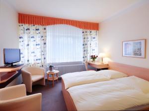 a hotel room with two beds and a desk at Hotel Restaurant Lüdenbach in Overath