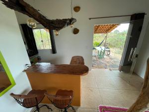 a kitchen with a counter and chairs in a room at Chalé jatobá, venha viver essa experiência!!! in Alto Paraíso de Goiás