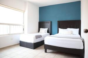 two beds in a room with a blue wall at Linda Vista, la mejor ubicación, 5 min Fundidora - LV2 - in Monterrey