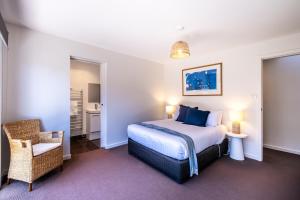 een slaapkamer met een kingsize bed en een stoel bij Freycinet Haven in Coles Bay