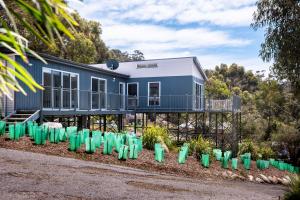 een blauw huis met groene containers ervoor bij Freycinet Haven in Coles Bay
