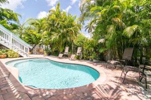 a swimming pool with chairs and palm trees at Sail Away Cottage in Bradenton Beach