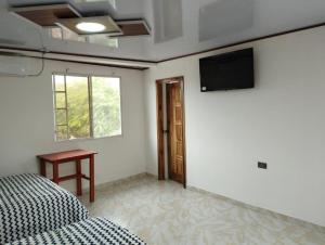 a bedroom with a bed and a television on the wall at Imelda House in Ayangue