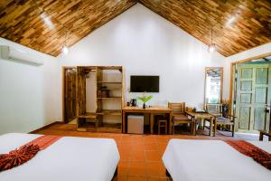 a bedroom with two beds and a desk and a tv at La Mer Resort, Phú Quốc in Phu Quoc