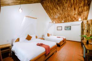 a bedroom with two beds and a wooden ceiling at La Mer Resort, Phú Quốc in Phú Quốc