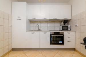 eine weiße Küche mit einer Spüle und einer Mikrowelle in der Unterkunft Apartments with a parking space Liznjan, Medulin - 21802 in Ližnjan