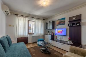 een woonkamer met een blauwe bank en een tv bij Apartments with a parking space Porec - 22124 in Poreč