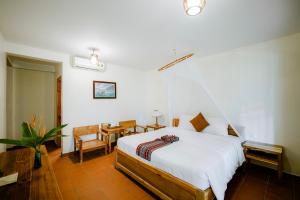 a bedroom with a bed and a table and chairs at La Mer Resort, Phú Quốc in Phú Quốc