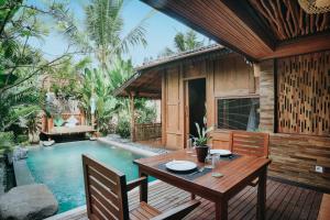 a wooden table and chairs next to a swimming pool at Candy Villa by Pramana Villas in Ubud