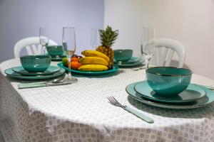 a table with green plates and wine glasses and fruit at Coliving7 Aparta Hotel & Habitaciones in Ibagué