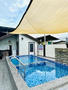 a swimming pool with a large umbrella over it at TeratakAyahBonda in Kuala Terengganu +12 photos