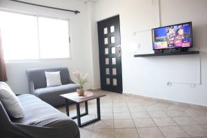 uma sala de estar com um sofá e uma televisão na parede em Amplio depa 10 min Parque Fundidora, Estadio BBVA - LV5 - em Monterrey