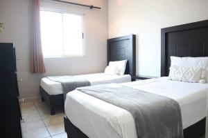 um quarto de hotel com duas camas e uma janela em Amplio depa 10 min Parque Fundidora, Estadio BBVA - LV5 - em Monterrey