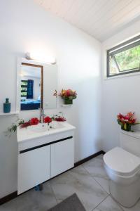 a white bathroom with a toilet and a sink at Matira Beach Raitea 1 in Bora Bora