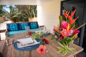 a table with a plate and a vase of flowers at Matira Beach Raitea 1 in Bora Bora