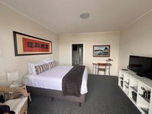 a bedroom with a bed and a flat screen tv at Mangonui Waterfront Apartments in Mangonui