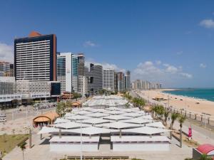 a beach with white umbrellas and buildings and the ocean at Via Venetto FEIRINHA in Fortaleza