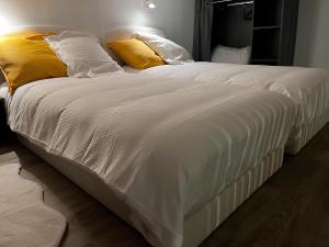 uma cama grande com lençóis brancos e almofadas amarelas em Tinyhouse Experience in Beaujolais em Villefranche-sur-Saône