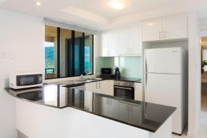 a kitchen with white cabinets and a white refrigerator at Pinnacles in Airlie Beach